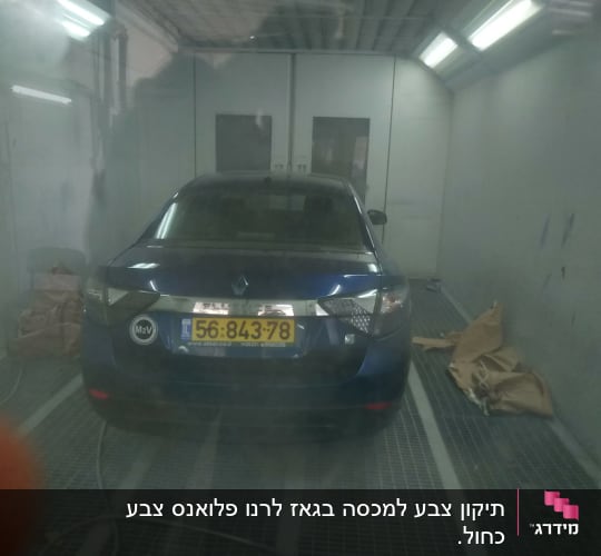 מכונית כחולה בתא צבע עם ניירות על הרצפה